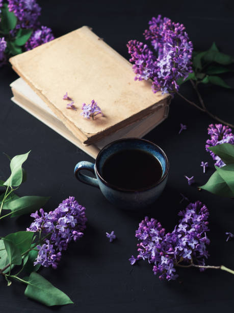 istock Spring lilac composition, lilac flowers, blue espresso coffee cup, old books on a black table, romantic greeting card 1303460123