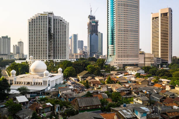 Contrast in Jakarta downtown district with modern skyscrapers, a large mosque and a very crowded low income residential district in Indonesia capital city Contrast in Jakarta downtown district with modern skyscrapers, a large mosque and a very crowded low income residential district in Indonesia capital city jakarta slums stock pictures, royalty-free photos & images