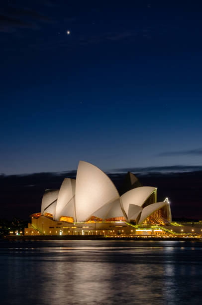 Sydney Australia - August 4, 2019: Early morning in Sydney, and the illuminated roof of the city's famous Opera House is reflected in the waters of Circular Quay.