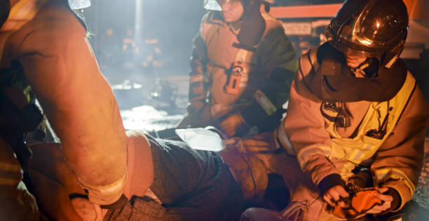 istock Firefighters helping injured man 1303463172