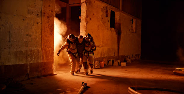 Senior man being rescued by firefighters Firefighters helping injured senior man while walking at gas explosion site on street. victim advocacy stock pictures, royalty-free photos & images