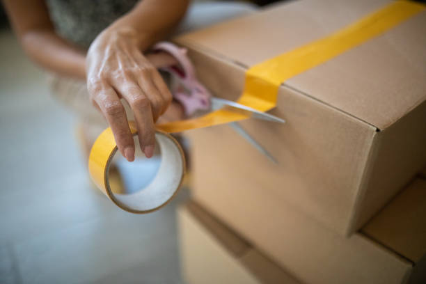 istock Woman closing a cardboard box with adhesive tape in her e-commerce store 1303466295
