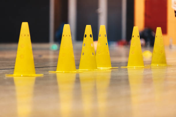 Row of Yellow Sports Training Cones on Shiny Surface of Wooden Sports Floor. Indoor Soccer, Basketball Training Field Row of Yellow Sports Training Cones on Shiny Surface of Wooden Sports Floor. Indoor Soccer, Basketball Training Field sports training drill stock pictures, royalty-free photos & images