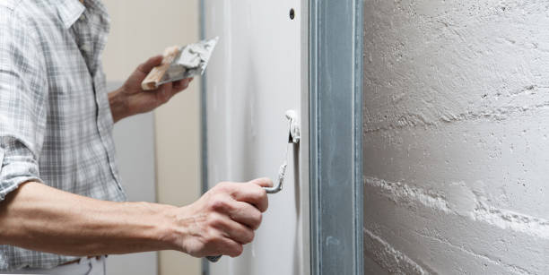 istock closeup hands man drywall worker or plasterer putting stucco on plasterboard wall using a trowel and a spatula, fill the screw holes 1303468986