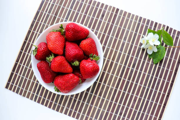 istock ripe fresh strawberries on a white plate and jasmine flowers 1303469084