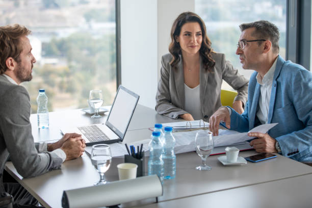 istock Senior manager explaining new investment to colleagues using plan on spreadsheet 1303473344