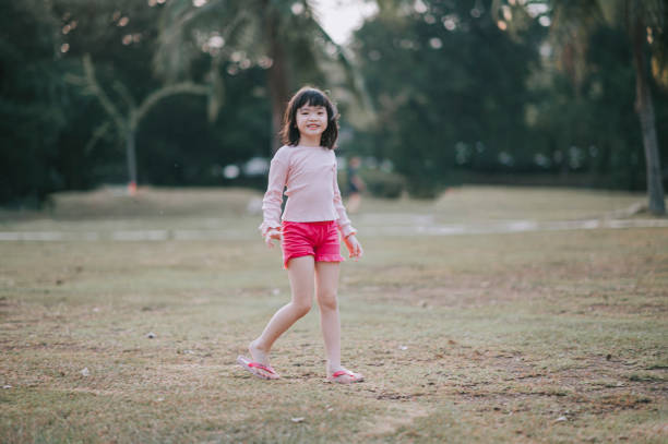 fille chinoise asiatique de 6 ans regardant l’appareil-photo dans le stationnement pendant le soir - female 8 9 years child excitement photos et images de collection