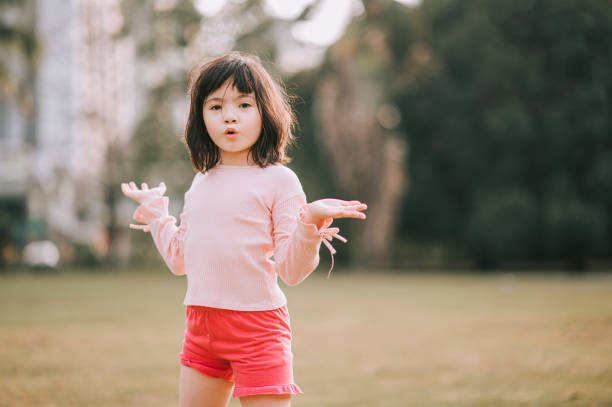 fille chinoise asiatique de 6 ans regardant l’appareil-photo dans le stationnement pendant le soir - female 8 9 years child excitement photos et images de collection