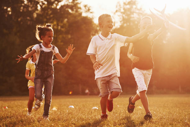 istock Group of kids have active weekend in the field. Illuminated by beautiful sunlight 1303475190