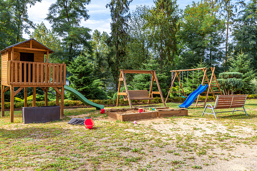 Empty modern wooden children playground set on green yard in public park in summer day. Funny toy land for kids. Urban exercise activities for child outdoors. Neighborhood childhood concept