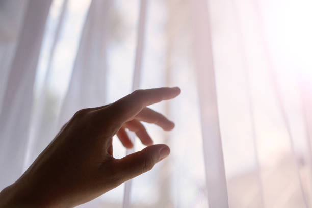 istock Woman's hand in the dark reaches for a bright window 1303479277