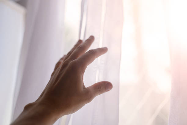 istock Man's hand in the dark reaches for a bright window 1303479316