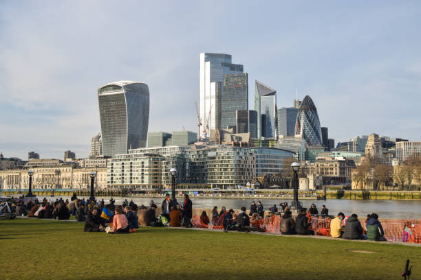 People in Potters Fields Park with a view of the City of London London, United Kingdom - February 20 2021: People enjoying the sunshine in Potters Fields Park next to Tower Bridge, with a view of the City of London skyline. waterloo bridge stock pictures, royalty-free photos & images