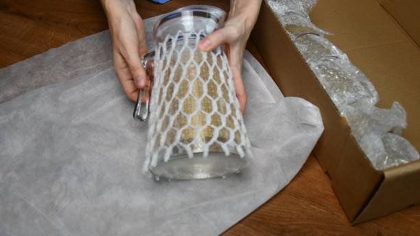 istock Female hands packing up glass jug into wrapping mesh to protect while moving 1303481245