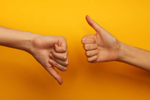 Thumbs up and down Two hands on a yellow background, one of them is with thumb up and other is with thumb down kyrgyzstan photos stock pictures, royalty-free photos & images