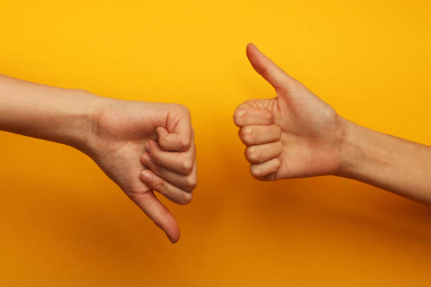 Thumbs up and down Two hands on a yellow background, one of them is with thumb up and other is with thumb down thumbs down stock pictures, royalty-free photos & images