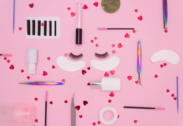 istock Eyelash extension tools, artificial eyelashes and red hearts on a pink background. Tools for the lashmaker. The view from the top. 1303484081