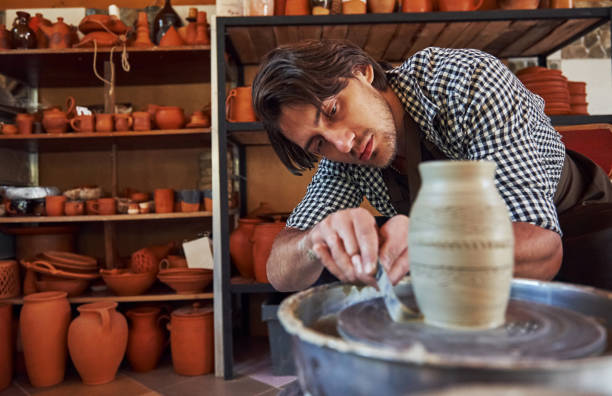 istock Detailing by special tool. Ceramist uses potter's wheel and creates a handmade clay product 1303484607