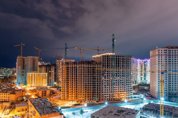 istock Construction site, cranes and multi-storey unfinished houses at night in winter 1303485610