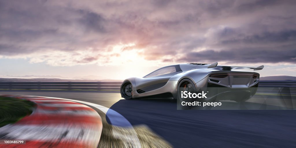 Electric Sports Car Moving At High Speed Around Racetrack Corner Rear side view of a generic silver electric sports car moving past a corner of a racetrack at high speed as sunrise / sunset. With motion blur to the track and also wheels. Sports Track Stock Photo