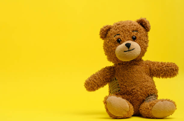 istock brown teddy bear sits on a yellow background 1303486159