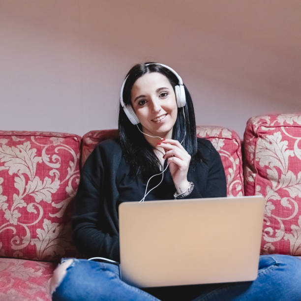 istock Young woman E-learning on internet with laptop on sofa 1303486960