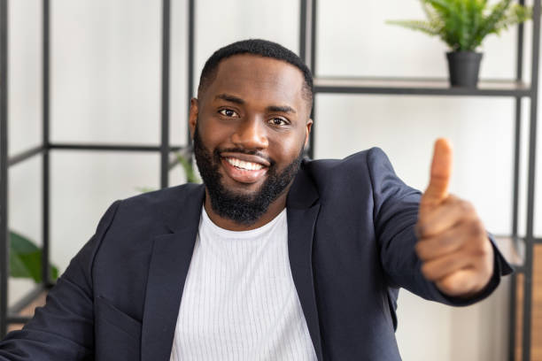 istock African american man smiling showing at camera thumbs up 1303487411