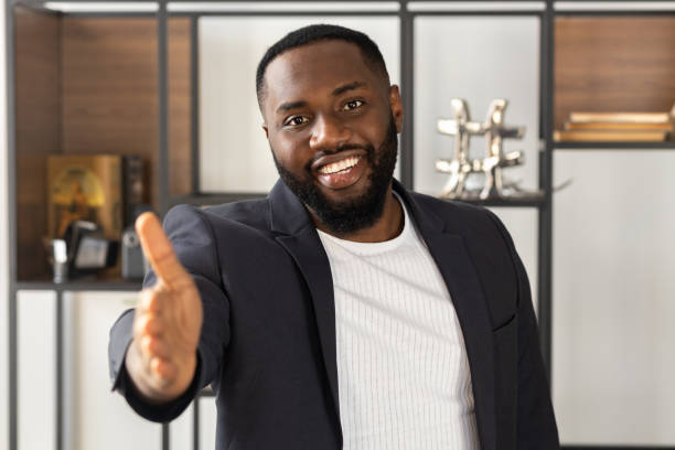 istock African american man smiling extending hand at camera handshake concept greeting 1303487420