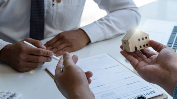 istock The insurance agent holds a small sample home design in hand, showing coverage for clients interested in insurance and home sales ideas. 1303489326