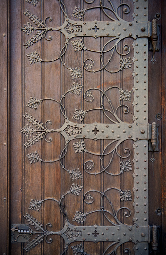Metal ornaments on a brown wooden church door.