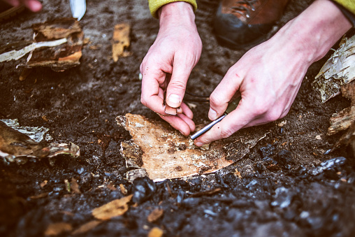 Man hands trying to make fire by flint in a forest.