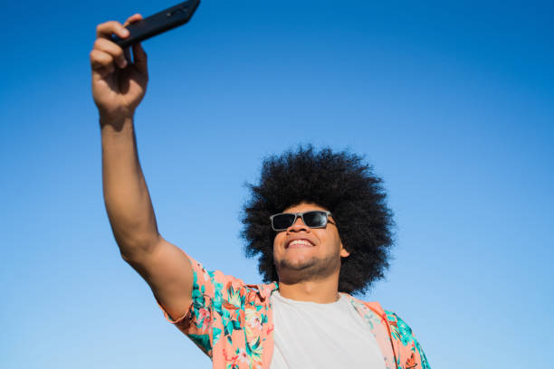 istock Latin man taking a selfie with phone outdoors. 1303497802