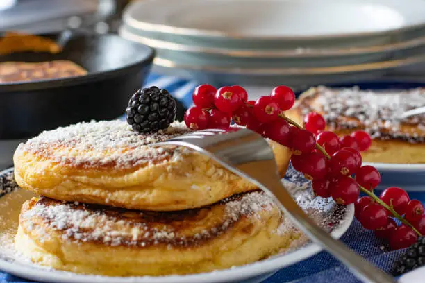 Closeup of fresh fluffy pancakes on a plate with berries melted butter and powdered sugar