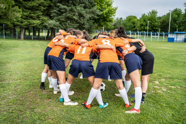 istock Women soccer team and coach hugging 1303499267