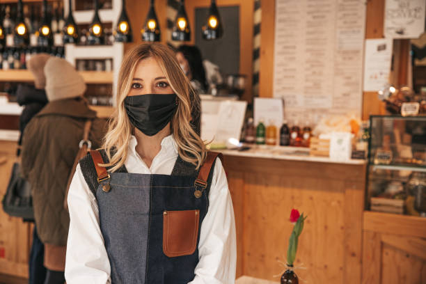 istock Waiter with a surgical mask posing in his bar 1303499399