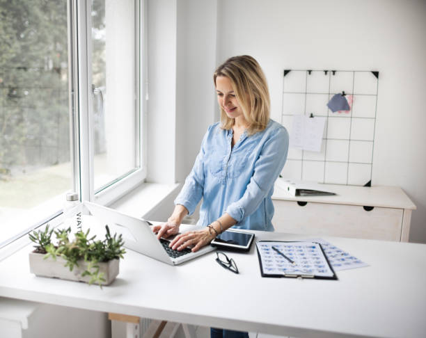 istock Businesswoman working at ergonomic standing workstation. 1303500400