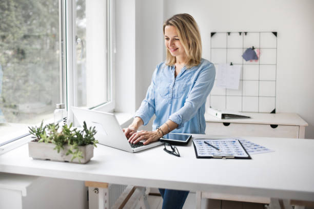 istock Businesswoman working at ergonomic standing workstation. 1303500436