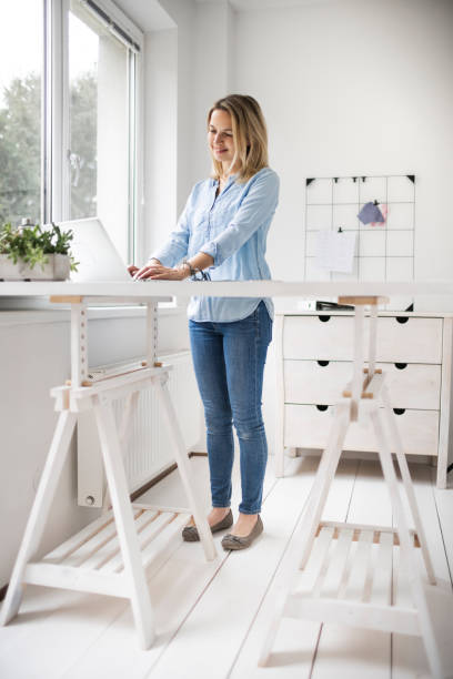 istock Businesswoman working at ergonomic standing workstation. 1303500475