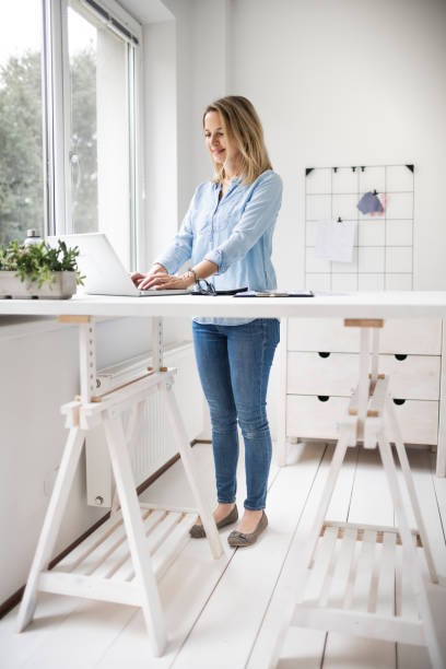 istock Businesswoman working at ergonomic standing workstation. 1303500481