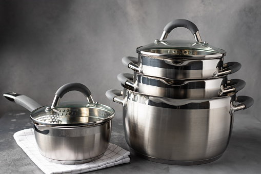Stainless steel kitchenware against dark gray background. New cooking utensils. copy space