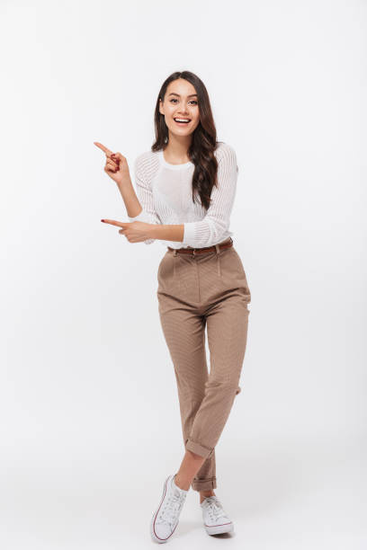 Full length portrait of a smiling asian businesswoman Full length portrait of a smiling asian businesswoman standing and pointing fingers away isolated over white background pointing stock pictures, royalty-free photos & images