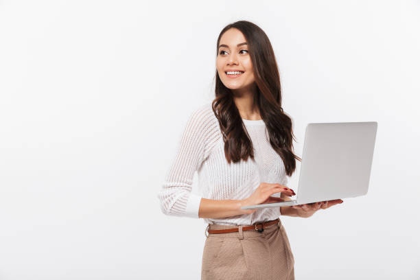 Portrait of a happy asian businesswoman Portrait of a happy asian businesswoman holding laptop computer iand looking away solated over white background isolated color photos stock pictures, royalty-free photos & images