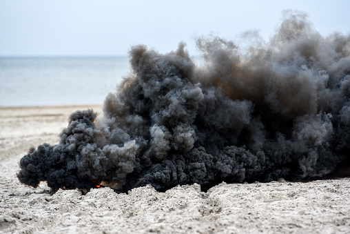Explosion on the beach, billowing black smoke.