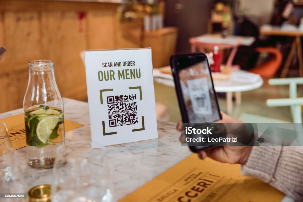 Woman consulting the restaurant menu with QR Code Friends in a restaurant scanning Online Food and Drinks menu QR Code Stock Photo