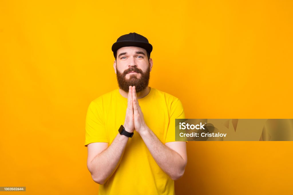 Please, photo of young bearded man praying for something Please, photo of young bearded man praying for something. Hipster Culture Stock Photo
