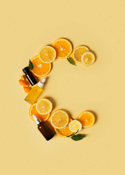 Bottles of serum of vitamin c and orange, lemon and green leaf flat lay on yellow background Bottles of serum of vitamin c and orange and green leaf flat lay on yellow background, copy space, top view, vertical ascorbic acid stock pictures, royalty-free photos & images