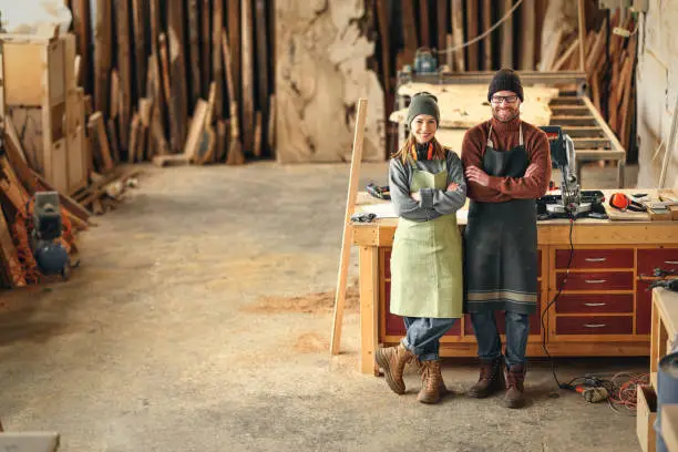 Photo of Positive carpentry workshop owners standing near workbench