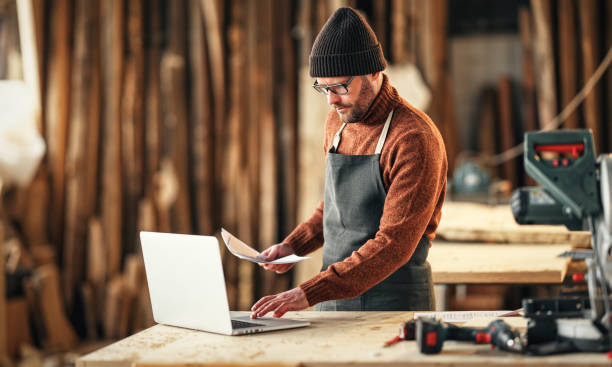 istock Craftsman working with laptop and papers in workshop 1303505688