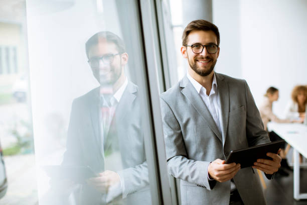 istock Young modern businessman using digital tablet in the office 1303505944