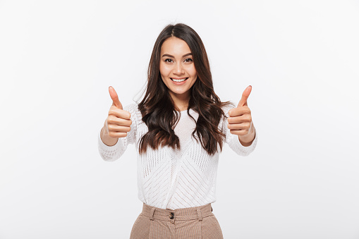 Portrait of a smiling asian businesswoman showing thumbs up isolated over white background